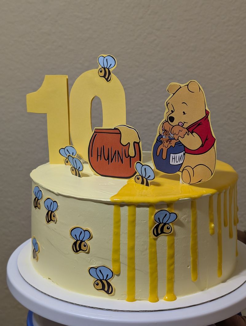 Winnie the Pooh themed first birthday cake topper on a yellow buttercream cake